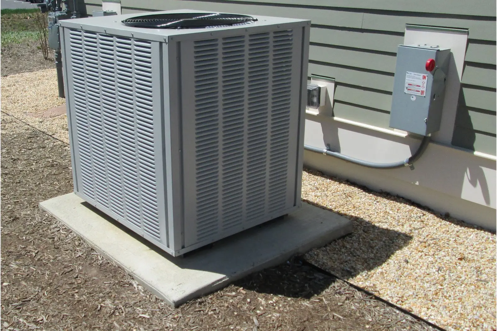New central air condenser installed on a concrete pad beside a house