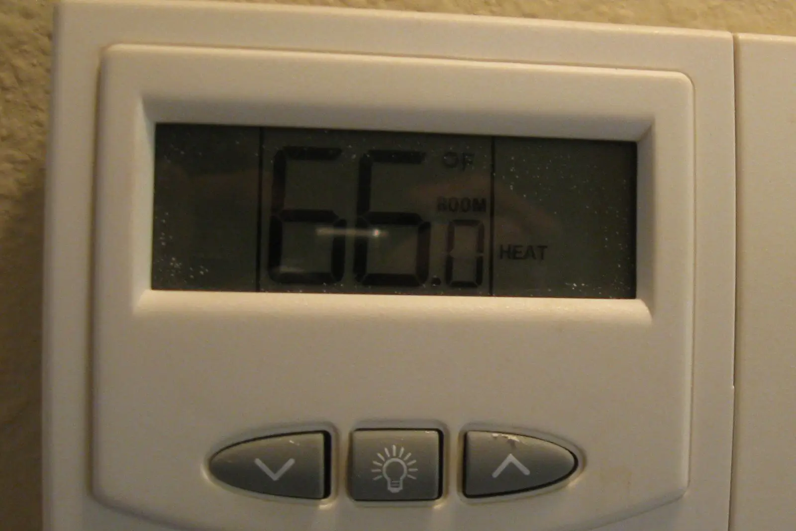 Digital wall thermostat set to heat showing 66 degrees