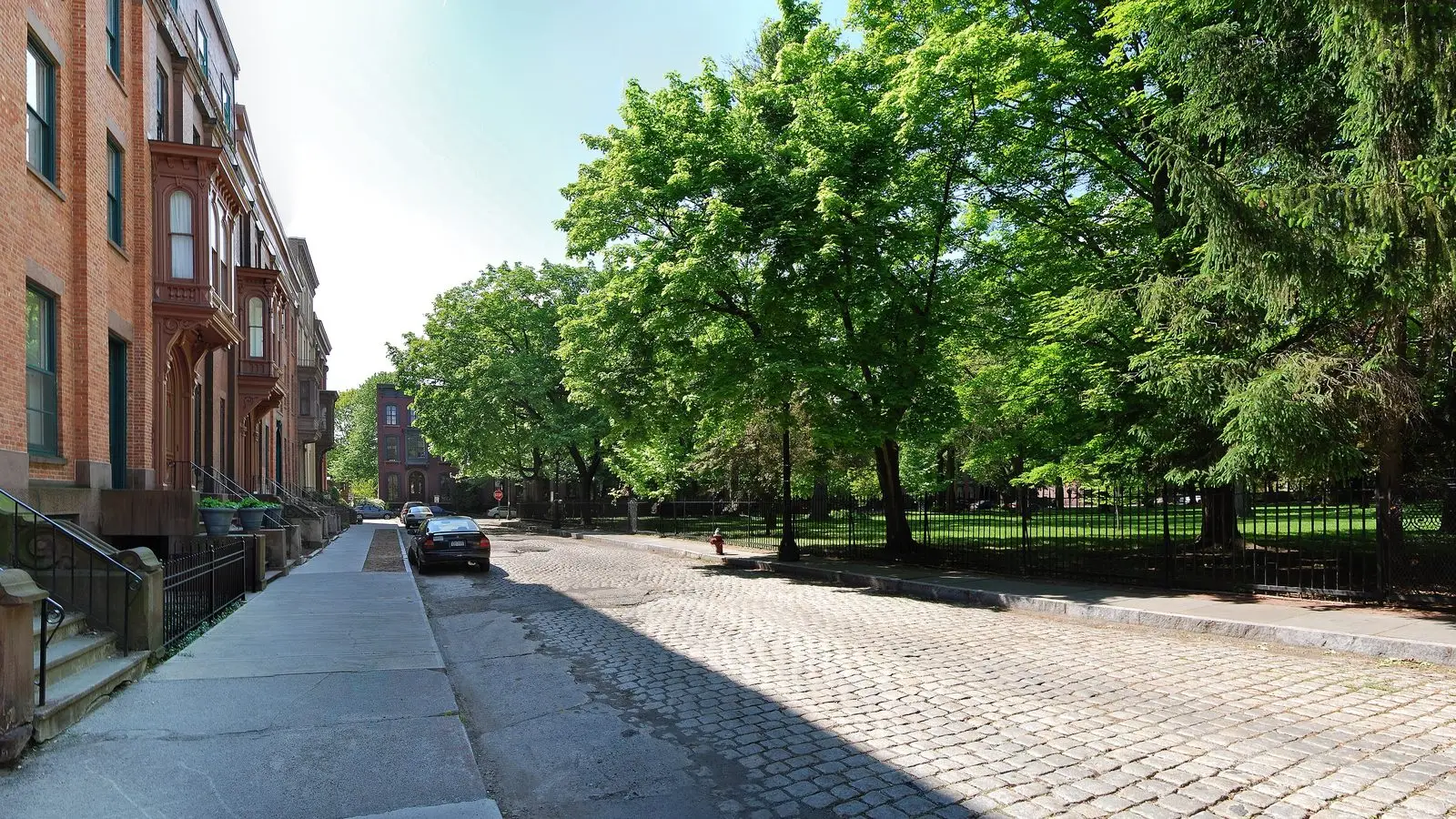 Brownstone rowhouses and cobblestone street along Washington Park in Troy